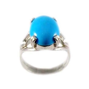 May include: A silver ring featuring a large, oval-shaped, bright turquoise stone. The stone is set in a silver band with decorative claw-like prongs holding the stone. The ring is set against a white background.