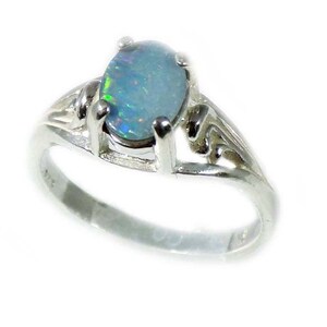 May include: A silver ring with an oval-shaped opal gemstone. The ring has a delicate, ornate design.
