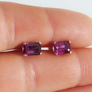 Puede incluir: Un par de pendientes de plata con piedras preciosas rectangulares de color púrpura.