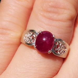 May include: A silver ring with a red ruby gemstone set in a filigree design.