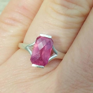 Puede incluir: Un anillo de plata con una piedra preciosa rosa engastada en una forma rectangular facetada.