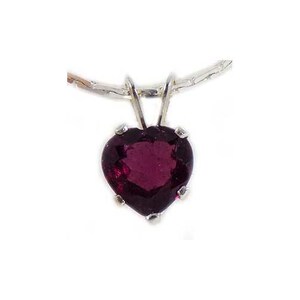 May include: A heart-shaped pendant with a deep red gemstone, suspended from a silver chain. The gemstone is faceted, catching the light and displaying a rich, dark color. The pendant is a classic jewelry piece.