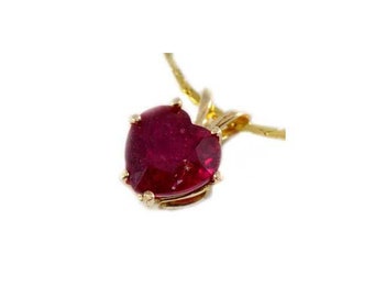 May include: A heart-shaped, deep red gemstone pendant on a gold chain. The gemstone is set in a gold bezel with four prongs. The chain is a delicate, twisted design, and the background is white.