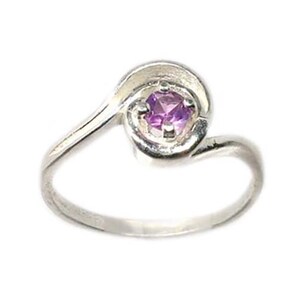 May include: A silver ring with a swirling design. The ring features a small, square-cut purple gemstone set in the center of the swirl. The band is smooth and polished, creating a simple yet elegant piece of jewelry.