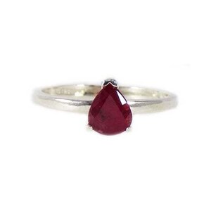 May include: A silver ring with a pear-shaped ruby gemstone.