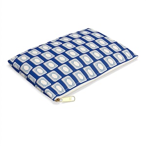 May include: A rectangular, zippered pouch with a repeating pattern of off-white rectangles outlined in blue on a blue background. The zipper is gold-colored.