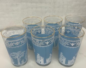 Può includere: Set di sei bicchieri vintage blu e bianchi. Ogni bicchiere presenta uno sfondo azzurro con motivi e figure decorative bianche e un bordo dorato. I bicchieri sono alti circa 13 cm.