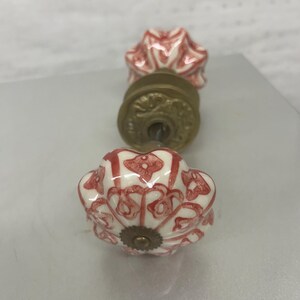 Tiradores de puerta de porcelana blanca con diseños rojos pintados a mano y herrajes de latón.
