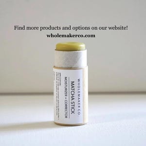 May include: A Matcha Stick moisturizer and corrector by Wholemaker Co. The product is in a cylindrical container with a light green top. The label includes the text "MOISTURIZER + CORRECTOR" and "MATCHA STICK". The website is wholemakerco.com.