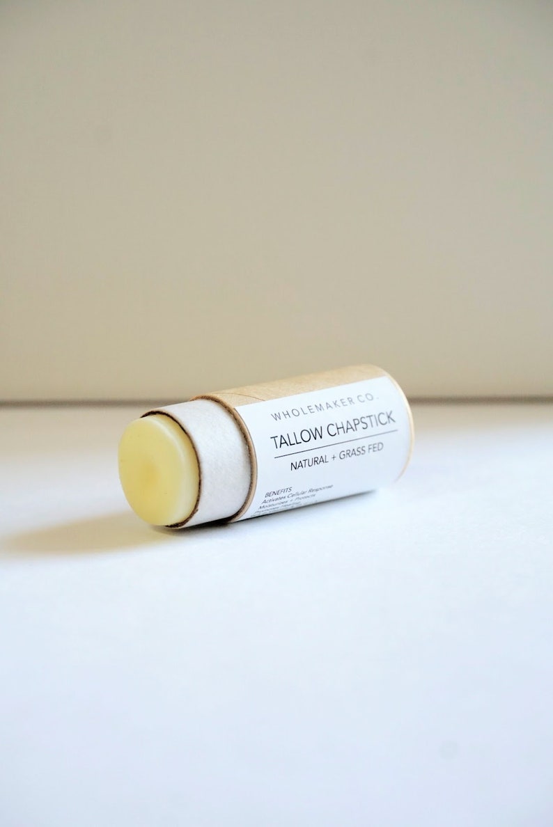 May include: A cylindrical tallow chapstick with a light yellow balm. The product is in a cardboard tube with a white label that reads "Tallow Chapstick Natural + Grass Fed" and "Whole Maker Co."