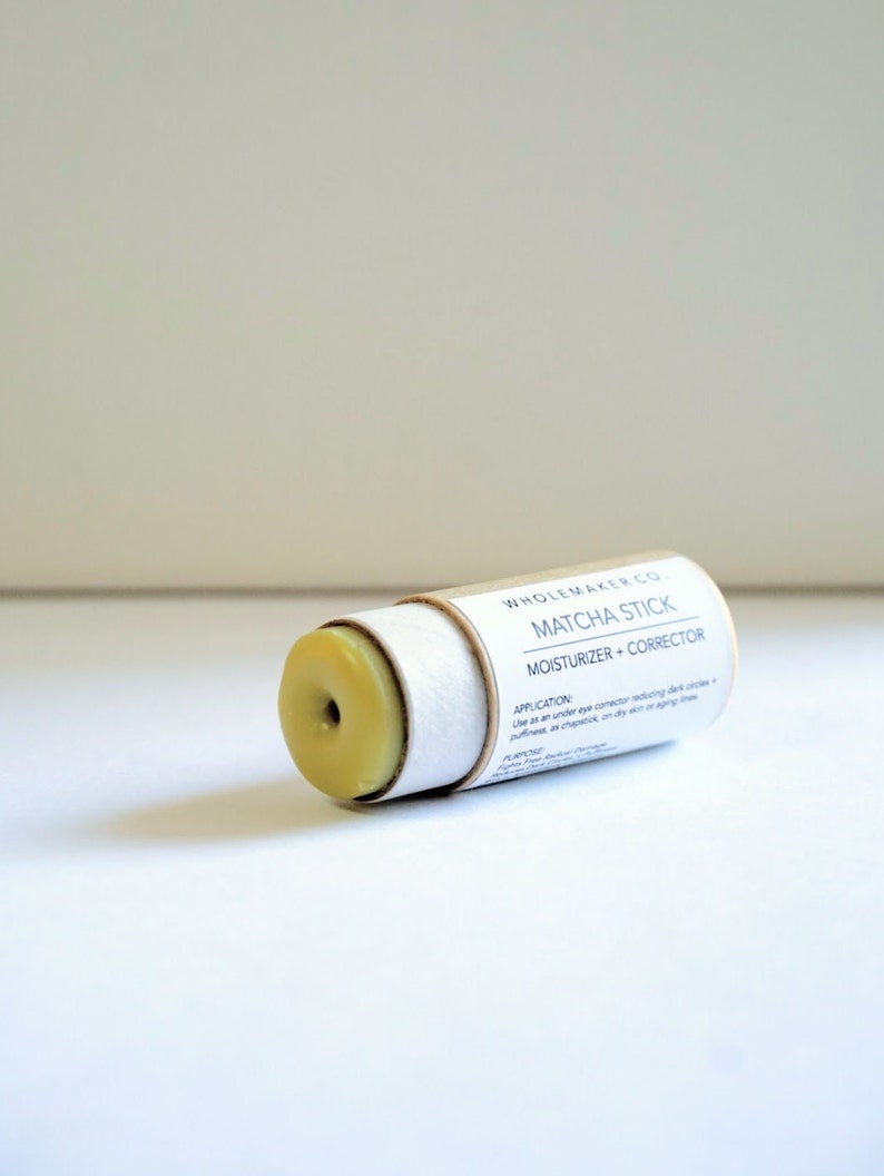 May include: A matcha stick moisturizer and corrector in a cylindrical cardboard tube. The product is light green and has a hole in the center. The text "WHOLEMAKER CO." and "MATCHA STICK" are printed on the tube.