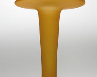 May include: A mustard-colored glass vase with a round base, a long, slender neck, and a wide, flat top. The vase has a matte finish and a smooth texture. The vase is likely used for decorative purposes.
