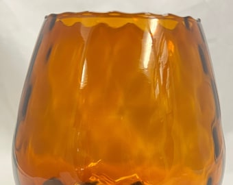 May include: A large amber glass vase with a wide, round base and a wavy, textured design. The vase has a dark brown stem and base.