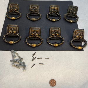 Pode incluir: Oito botões de armário de latão antigo com designs ornamentados e um conjunto de parafusos para instalação.