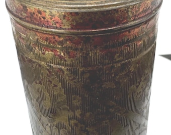 May include: A cylindrical metal container with a conical lid, featuring a weathered gold and reddish-brown finish. The surface is decorated with intricate, embossed linear patterns and floral motifs that wrap around the body and the lid.