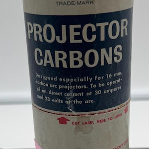 May include: A white cardboard tube with a blue label that reads "National Pearlex Projector Carbons". The label also states "Designed especially for 16 mm. carbon arc projectors. To be operated on direct current at 30 amperes and 28 volts at the arc."