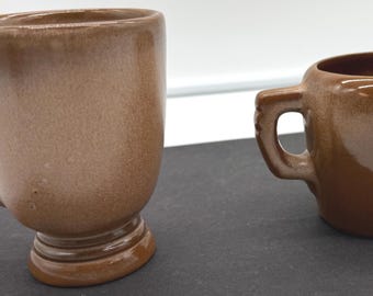 May include: A brown ceramic mug and creamer set. The mug has a pedestal base and a decorative handle. The creamer has a small handle and a spout. Both pieces have a speckled finish.