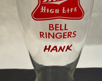 May include: A clear glass beer stein with a red Miller High Life logo and the words "Bell Ringers Hank" printed in red.