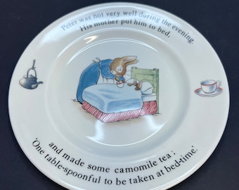 May include: A white ceramic plate with a picture of a bunny in bed. The plate has text that reads: "Peter was not very well during the evening. His mother put him to bed. 'One table-spoonful to be taken at bed-time. and made some camomile tea:'"