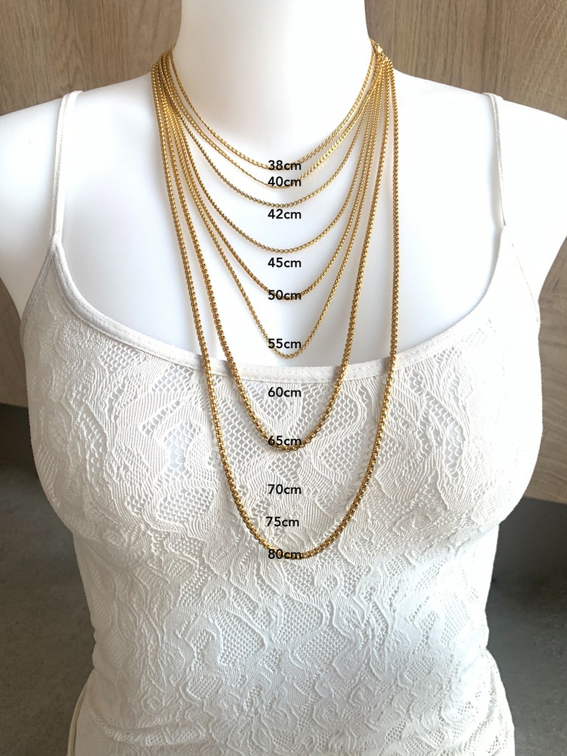 May include: A gold chain necklace in various lengths from 38 to 80 centimeters. The necklace is displayed on a white mannequin.