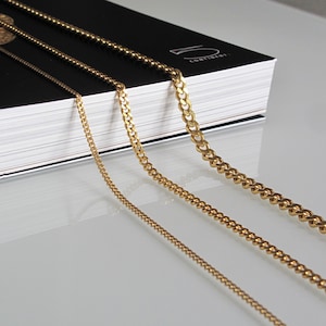 May include: Four gold chains of different thicknesses and styles, laid out on a white surface. The chains are arranged in order of size, with the thickest chain at the top and the thinnest chain at the bottom.