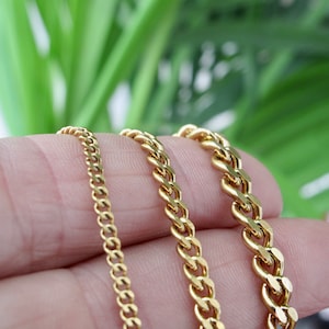 May include: Three gold chains of different widths and lengths. The chains are arranged in a row, with the thinnest chain on the left and the thickest chain on the right.