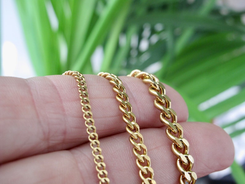 May include: Three gold chains of different widths and lengths. The chains are arranged in a row, with the thinnest chain on the left and the thickest chain on the right.