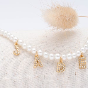Collar de perlas personalizado con nombre, zodiaco, números y letras adornado con circonita cúbica CZ en acabado oro de 18 quilates.