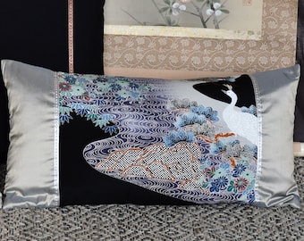 Könnte beinhalten: Ein schwarzes und silbernes Kissen mit einem weißen Vogel und einem Blumendesign. Das Kissen zeigt ein japanisch inspiriertes Muster mit einem Vogel, der auf einem Ast mit Blumen und Wasser steht.