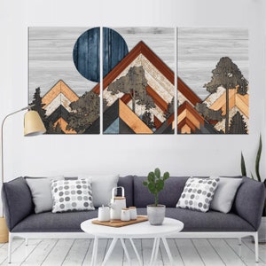 May include: A three-panel wooden wall art piece depicting a mountain landscape. The artwork features geometric mountain shapes in shades of brown, orange, gray, and blue, with a dark blue circle representing the sun or moon. Trees are also incorporated into the design.