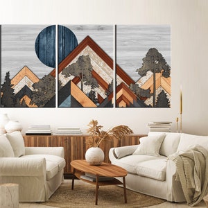 May include: A three-panel wooden wall art piece featuring a mountain landscape design. The artwork incorporates geometric shapes and natural wood tones, with a blue circle representing the sun or moon. Trees are also included in the design.