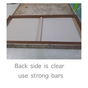 May include: The back of a canvas painting with a wooden frame. The canvas is stretched over the frame and the back is clear. The frame is made of wood and has a brown finish. The canvas is white and has a smooth surface. The frame is attached to the canvas with staples. The back of the canvas is clear and shows the staples that attach the canvas to the frame.