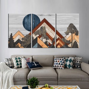 May include: A three-panel wooden wall art piece depicting a mountain landscape with a blue moon. The artwork features layered wood in shades of brown, orange, gray, and blue, with tree silhouettes. The background is a light gray wood grain.