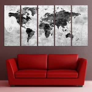 May include: A black and white world map print in a three-panel canvas set. The map is on a textured background with a distressed look. The map is displayed above a red couch.