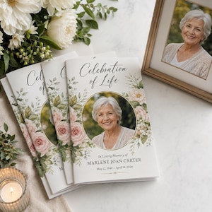 May include: A funeral program booklet titled Celebration of Life featuring a circular portrait of an older woman with short gray hair. The cover is decorated with soft pink roses and green foliage, displaying the name Marlene Joan Carter.