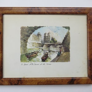 May include: A framed watercolor painting depicting a view of the Seine River in Paris, France. The painting shows the Notre Dame Cathedral in the background, with a bridge and boats in the foreground. The text "9. Bord de la Seine et de la " is written in the bottom right corner of the painting.