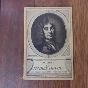 May include: A vintage book cover featuring a black and white portrait of Moli&egrave;re, the French playwright. The title of the book is "Moli&egrave;re Les Femmes Savantes" with the words "Classiques Illustres V.AUBOURDOILLE" and "Librairie Hachette" printed below.