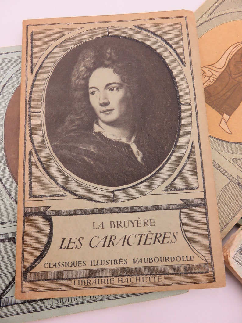 May include: A vintage book cover featuring a portrait of a man with long curly hair. The title is "La Bruy&egrave;re Les Caract&egrave;res" with the text "Classiques Illustr&eacute;s Vaubourdolle Librairie Hachette" below.