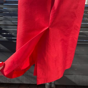 Puede incluir: Una falda roja brillante con una abertura en la espalda. La falda est&aacute; hecha de una tela suave y sedosa.