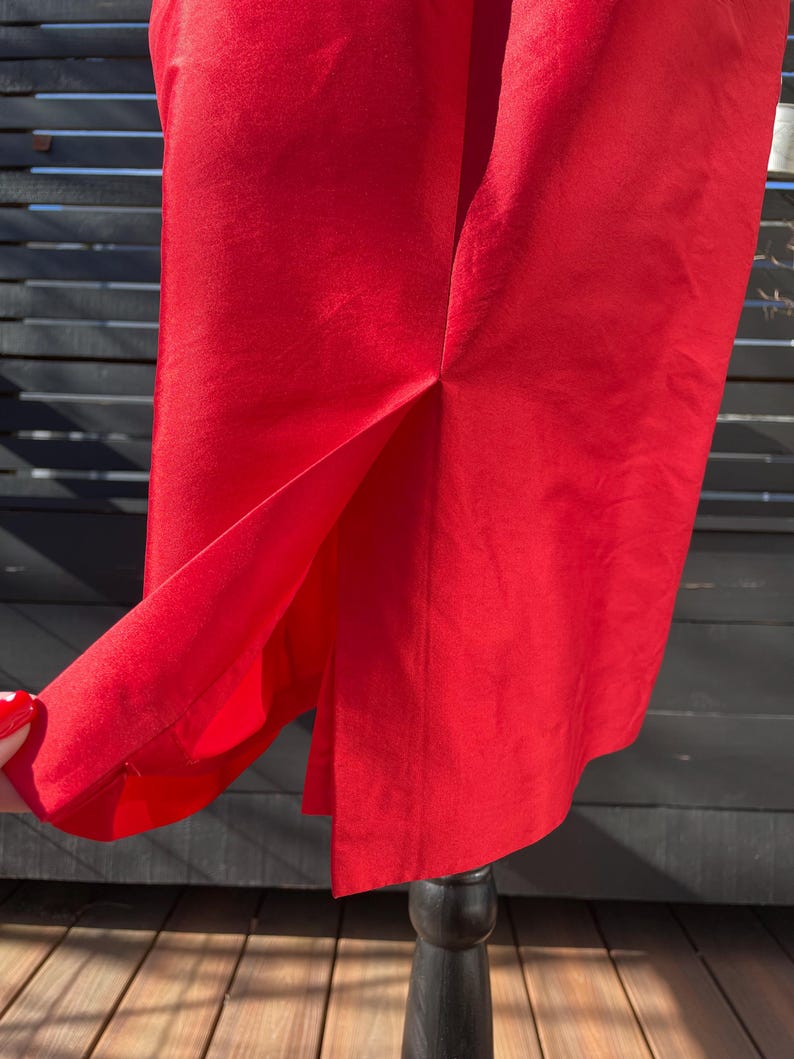 Puede incluir: Una falda roja brillante con una abertura en la espalda. La falda est&aacute; hecha de una tela suave y sedosa.