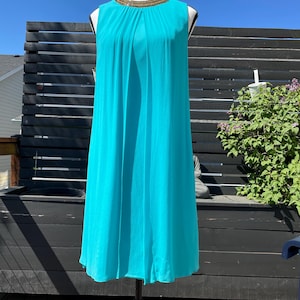 May include: A sleeveless turquoise dress with a gold beaded neckline. The dress is made of a lightweight fabric and has a flowing silhouette.