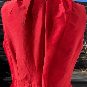 Puede incluir: Un vestido rojo sin mangas con una cremallera en la espalda.