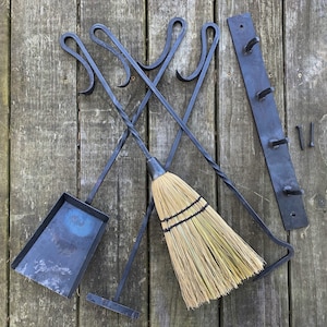 May include: A set of black metal fireplace tools with a matching wall-mounted rack. The tools include a poker, tongs, and a shovel. A natural fiber broom is also included.