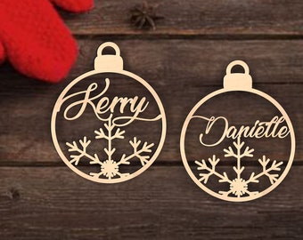 May include: Two wooden Christmas ornaments with snowflake designs and the names "Kerry" and "Danielle" written in cursive.