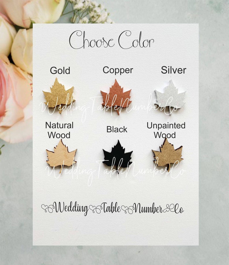 Puede incluir: Un gr&aacute;fico que muestra diferentes opciones de color para los n&uacute;meros de mesa de hoja de arce de madera. Los colores incluyen dorado, cobre, plateado, madera natural, negro y madera sin pintar.