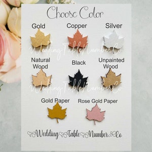 May include: Choose a color for your wedding table number: gold, copper, silver, natural wood, black, unpainted wood, gold paper, or rose gold paper. The table numbers are shaped like maple leaves.