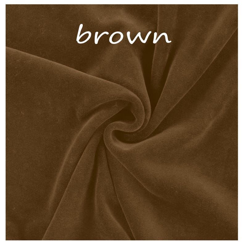 Op de afbeelding: Een stuk bruine fluwelen stof met een zachte, matte textuur en zichtbare plooien die natuurlijke schaduwen cre&euml;ren. Het woord brown is in witte, kleine, schreefloze letters bovenaan in het midden van het stofoppervlak gedrukt.