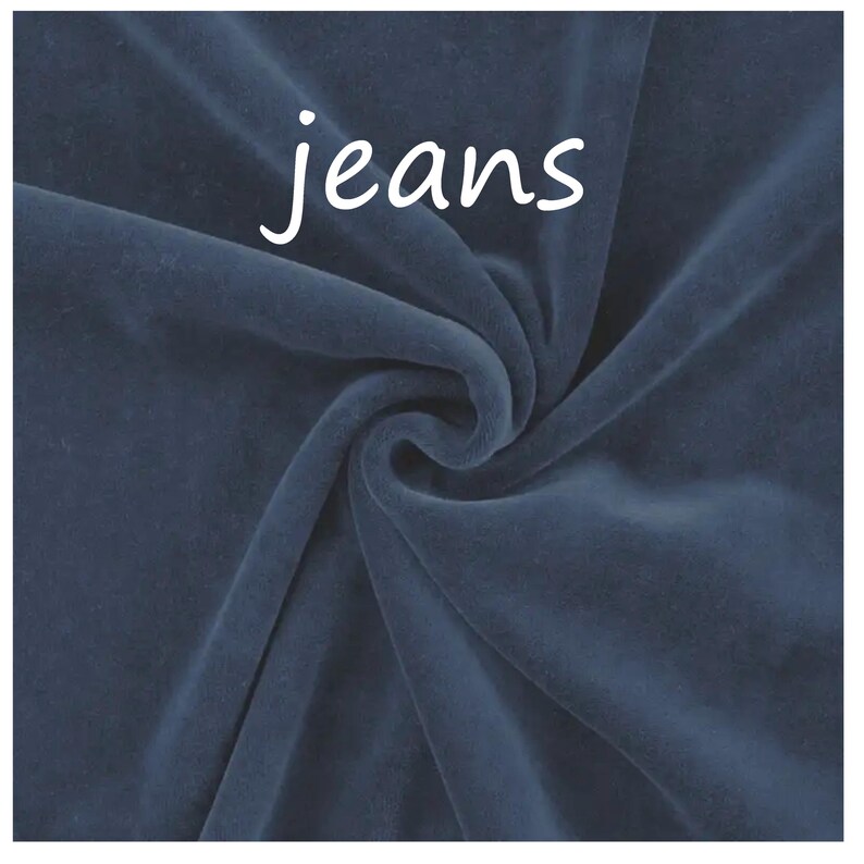Op de afbeelding: Een donkerblauwe fluwelen stof met een zachte, pluche textuur en een wervelend draperingspatroon. Het woord jeans is in witte, kleine, schreefloze letters in het midden bovenaan de stof gedrukt, wat contrasteert met de diepblauwe kleur.