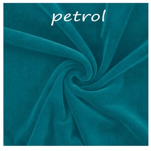 Op de afbeelding: Een staal van petrolblauwe fluwelen stof met een zachte, pluche textuur en natuurlijke plooien en rimpelingen die licht en schaduw cre&euml;ren. Het woord petrol is in witte, kleine, schreefloze letters bovenaan de afbeelding gedrukt.