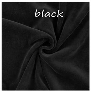 Op de afbeelding: Een stuk effen zwarte stof met een zachte, fluweelachtige textuur en een matte afwerking. Het materiaal is in het midden gedrapeerd om natuurlijke plooien en schaduwen te cre&euml;ren. Het woord "black" staat in witte tekst bovenaan de afbeelding.